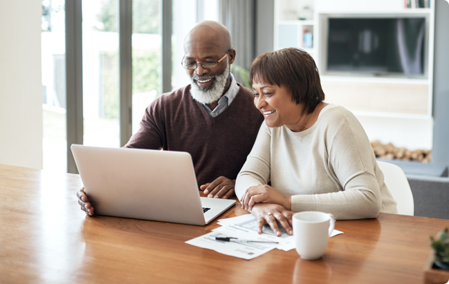 Smiling senior couple looks at laptop together